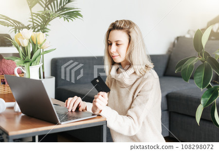 Young woman holding credit card and using laptop. 108298072