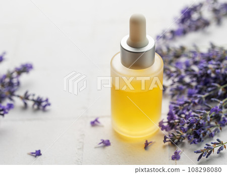 Lavender natural essential oil and fresh lavender on a white tile background. Lavender natural essential oil and fresh lavender on a white tile background. 108298080