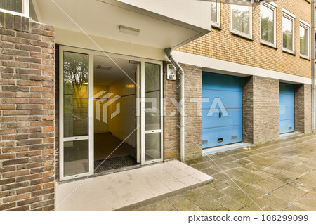a brick building with two blue garage doors on the side and an open door at the other one is visible 108299099