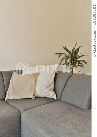a living room with a gray couch and white pillows on the sofa is next to a large potted plant a living room with a gray couch and white pillows on the sofa is next to a large potted plant 108299101