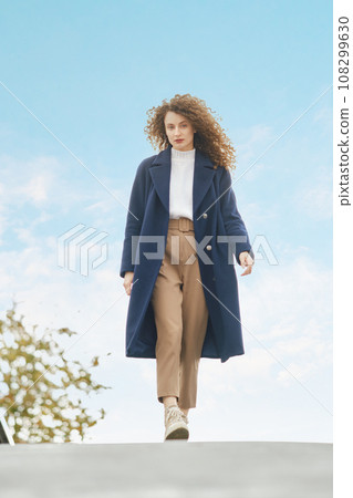 Woman in wool coat walks on the bridge in sunny day Woman in wool coat walks on the bridge in sunny day 108299630