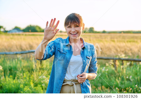 Portrait of smiling middle aged woman looking at camera, summer countryside Portrait of smiling middle aged woman looking at camera, summer countryside 108301926
