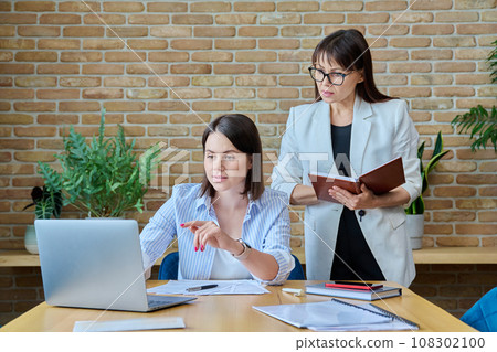 Two businesswomen talking and discussing in office 108302100