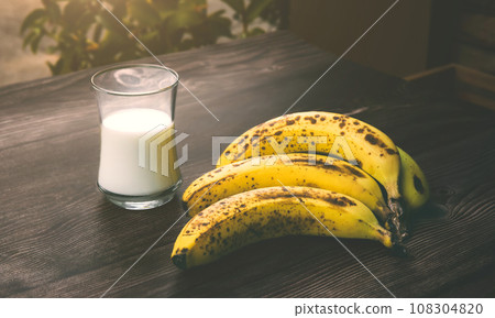 Ripe bananas on a wooden table with milk Ripe bananas on a wooden table with milk 108304820