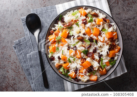 Fragrant rice with sweet potatoes, pecans, onions and dried cranberries close-up in a bowl. Horizontal top view 108305408