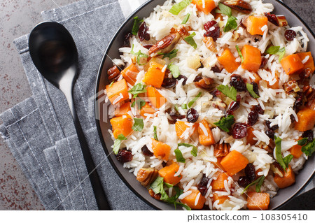 Delicious dietary rice with sweet potatoes, nuts, pecans, onions and dried cranberries close-up in a bowl. Horizontal top view Delicious dietary rice with sweet potatoes, nuts, pecans, onions and dried cranberries close-up in a bowl. Horizontal top view 108305410