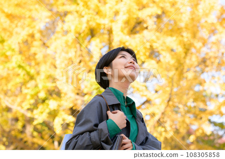A woman enjoying autumn leaves alone in a park A woman enjoying autumn leaves alone in a park 108305858