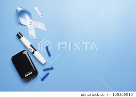 Diabetes awareness concept of ribbon glucose meter test strips and lancets on blue background flat lay. Diabetes awareness concept Diabetes awareness concept of ribbon glucose meter test strips and lancets on blue background flat lay. Diabetes awareness concept 108306010