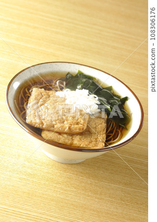 Hot fox soba with two pieces of fried tofu, wakame seaweed, and green onions. 108306176