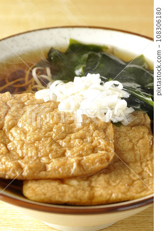 Hot fox soba with two pieces of fried tofu, wakame seaweed, and green onions. 108306180
