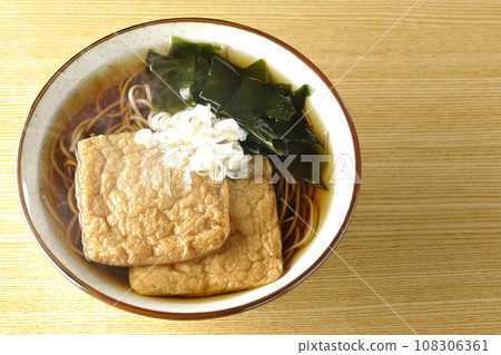 頭頂上的熱騰騰的狐狸蕎麥麵，上面放著兩片炸豆腐、海藻和大蔥。 108306361