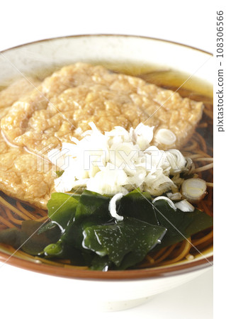 在白色背景下拍攝了熱狐狸蕎麥麵,上面放著兩片炸豆腐、海藻和大蔥。 在白色背景下拍攝了熱狐狸蕎麥麵,上面放著兩片炸豆腐、海藻和大蔥。 108306566