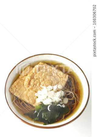 An overhead shot of piping hot fox soba noodles topped with two pieces of fried tofu, seaweed, and green onions against a white background An overhead shot of piping hot fox soba noodles topped with two pieces of fried tofu, seaweed, and green onions against a white background 108306702