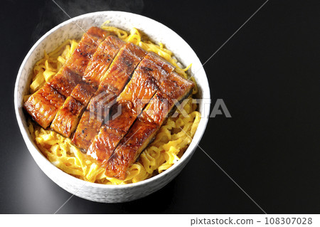 An overhead shot of a piping hot rice bowl of kinshi omelet and kabayaki eel against a black background An overhead shot of a piping hot rice bowl of kinshi omelet and kabayaki eel against a black background 108307028