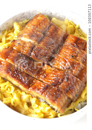 An overhead shot of a piping hot rice bowl of kinshi omelet and kabayaki eel against a white background An overhead shot of a piping hot rice bowl of kinshi omelet and kabayaki eel against a white background 108307113