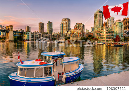 Canadian flag in front of ferry boat docked along in Granville island near Burrard Street Bridge at twilight in Vancouver,Canada 108307311
