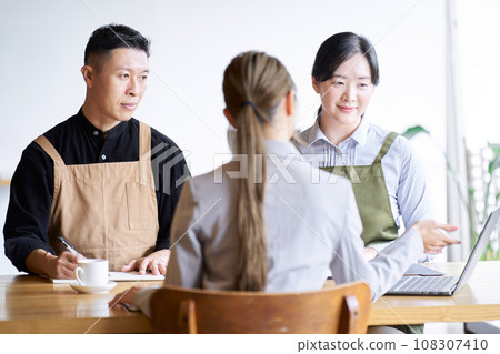 Restaurant manager listening to businesswoman's presentation 108307410