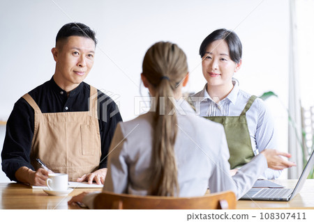 Restaurant manager listening to businesswoman's presentation 108307411