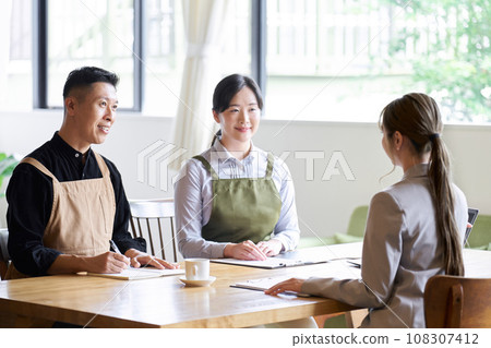 Restaurant manager listening to businesswoman's presentation 108307412