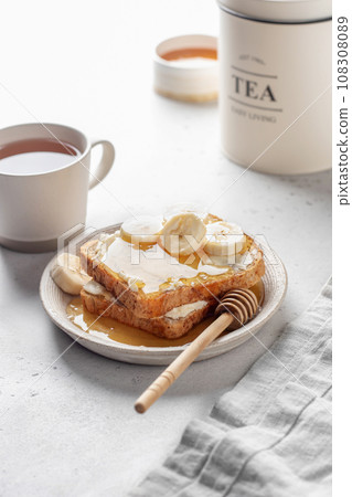 Toasts with butter, banana slices and honey on light kitchen background. Homemade breakfast sandwich. Healthy vegan food concept 108308089