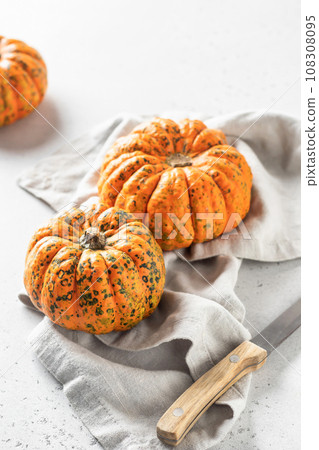 Whole mini pumpkins in composition with knife and linen napkin on white background with copy space Whole mini pumpkins in composition with knife and linen napkin on white background with copy space 108308095