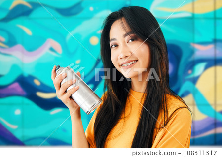 Smiling female street artist with spray paint can in hand looking to camera closeup 108311317