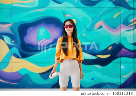 Female street artist standing near the wall with her paintings 108311318