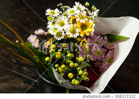 Paper wrapped chrysanthemums and other flowers delivered to the ikebana class 108311512