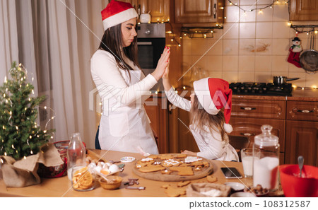 Two girls in santa hat spent time very happy at the kitchen. Christmas holidays 108312587
