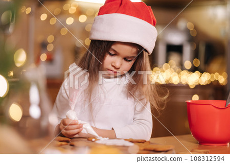 Mom with adorable little daughter spend time at kitchen in Christmas eve. Girls preparing sweets for holidays. Gingerbread and candy. Happy family Mom with adorable little daughter spend time at kitchen in Christmas eve. Girls preparing sweets for holidays. Gingerbread and candy. Happy family 108312594