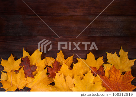 Frame from yellow autumn leaves on a brown wooden background. Fallen foliage. Backdrop for design. 108312819