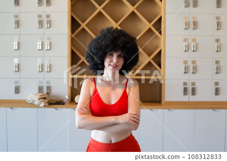 Athletic woman in a red top stands with her arms folded on her chest Athletic woman in a red top stands with her arms folded on her chest 108312833