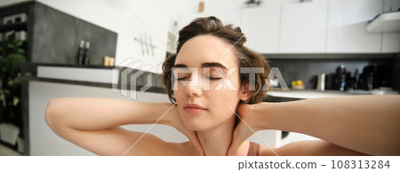 Fitness girl in activewear, doing yoga at home, stretching and working out, massaging her neck with pleased, relaxed face expression Fitness girl in activewear, doing yoga at home, stretching and working out, massaging her neck with pleased, relaxed face expression 108313284