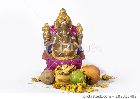 Ganesh Chaturthi is celebrated with a clay idol of Ganesh and flowers and fruits on white background. Ganesh Chaturthi is celebrated with a clay idol of Ganesh and flowers and fruits on white background. 108313492