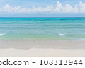 Sandy beach with rolling calm wave of ocean on sunny day on background white clouds in blue sky 108313944