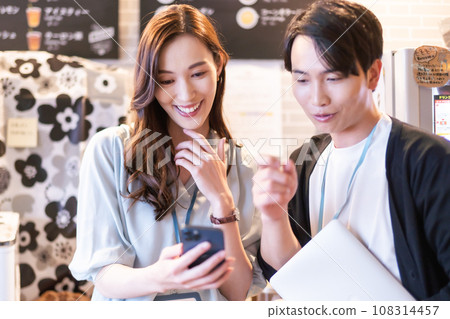 Business team talking while looking at mobile screen Business team talking while looking at mobile screen 108314457