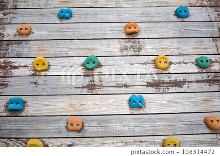 Climbing wall with colorful holds in the athletic section of the park Climbing wall with colorful holds in the athletic section of the park 108314472