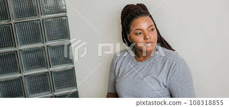 Beautiful African American woman with dreadlocks relaxing at home wearing gray t-shirt. Banner with copy space 108318855