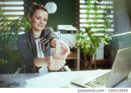 smiling business woman in green office stretching hands smiling business woman in green office stretching hands 108318946