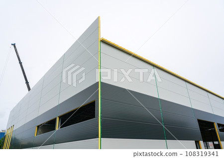 A new modern facade of an unfinished industrial facility made of gray sandwich panels A new modern facade of an unfinished industrial facility made of gray sandwich panels 108319341