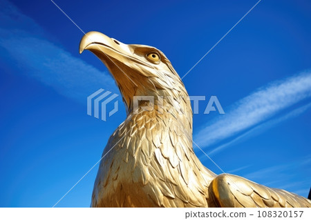 golden seagull statue against a blue sky 108320157