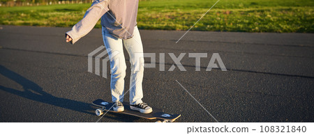 Cropped shot of legs on longboard. Skater girl riding her skateboard on street. Female teenager on cruiser Cropped shot of legs on longboard. Skater girl riding her skateboard on street. Female teenager on cruiser 108321840