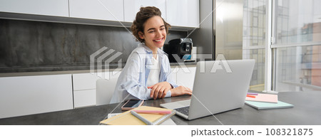 Portrait of smiling young woman connects to online webinar, studies at home on remote, looking at laptop with happy face, teacher people via tutor website Portrait of smiling young woman connects to online webinar, studies at home on remote, looking at laptop with happy face, teacher people via tutor website 108321875