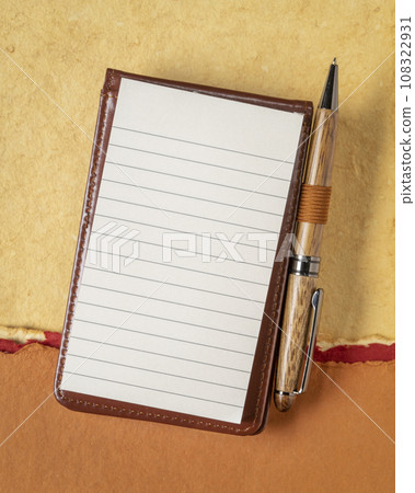 blank sheet of ruled paper in a small journal with a luxury pen against textured art paper blank sheet of ruled paper in a small journal with a luxury pen against textured art paper 108322931
