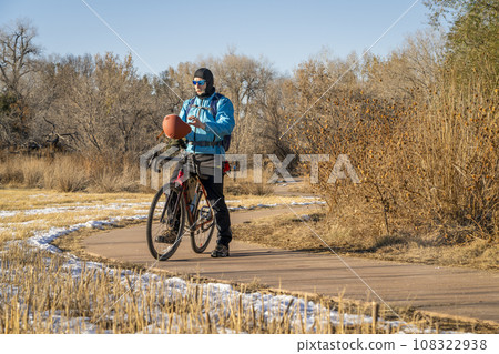 senior male cyclist with a touring gravel bike on a biking trail in Fort Collins, Colorado in cold fall weather with some snow 108322938