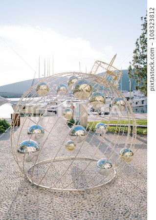 Christmas installation in the form of a Christmas ball with garlands stands on the pier Christmas installation in the form of a Christmas ball with garlands stands on the pier 108323812