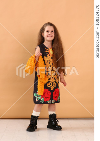 little model girl with long brown hair in designer floral dress, yellow jacket and military boots  108324570