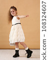 little model girl with long brown hair in designer white dress with belt, military boots full body photo walking. 108324607