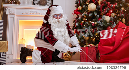 Santa Claus with red bag full of gifts for children at home. New year and Merry Christmas concept Santa Claus with red bag full of gifts for children at home. New year and Merry Christmas concept 108324796
