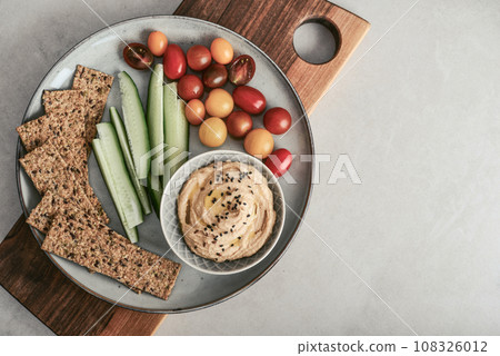 Bowl with hummus, cucumber, cherry tomatoes and crispbread 108326012